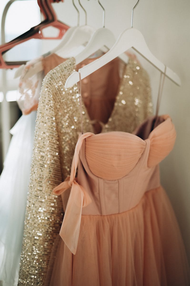 Peach and sequin dresses hanging elegantly on coathangers, perfect for fashion inspiration.